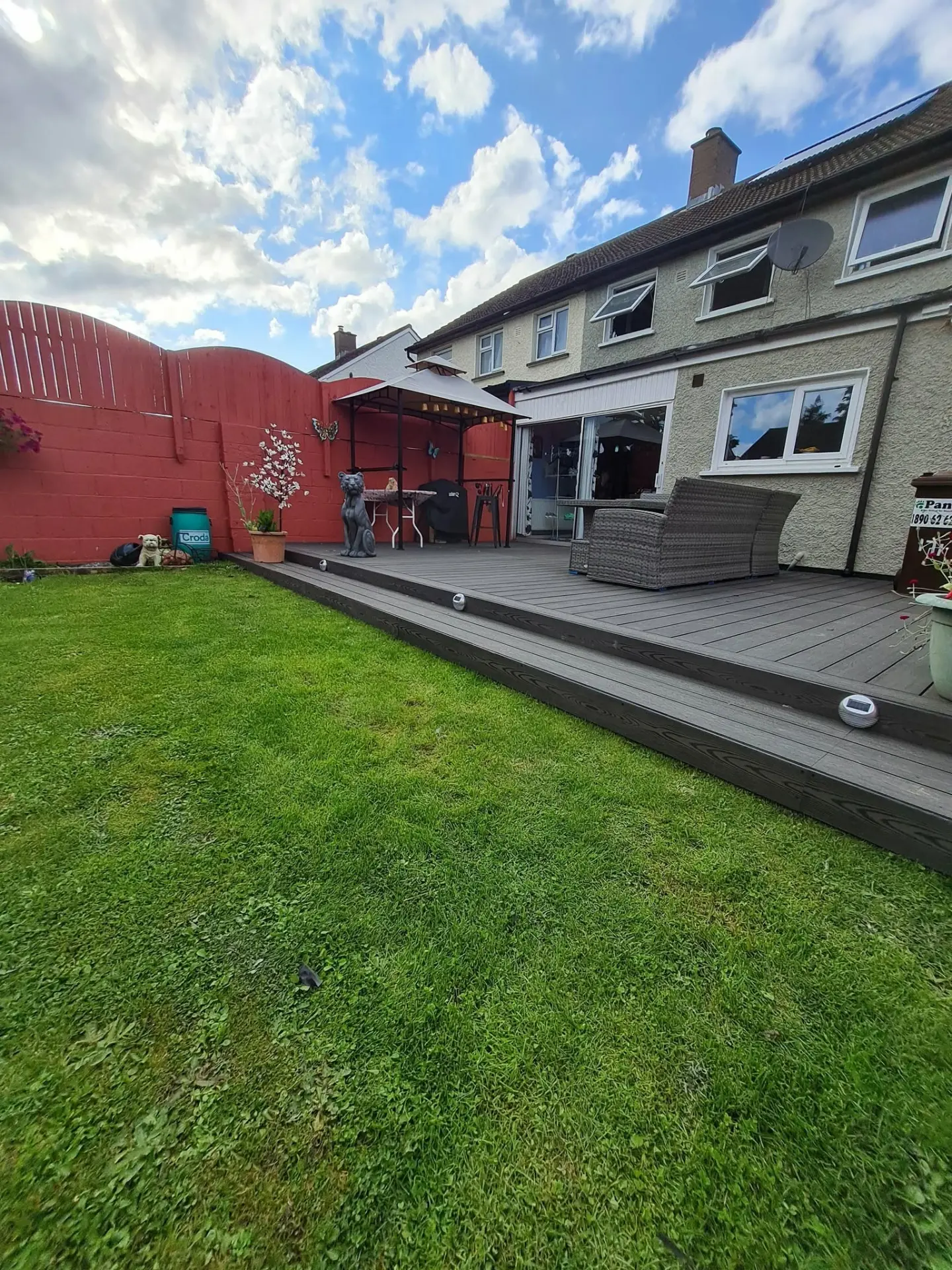 Grey composite decking patio with steps leading onto a lawn