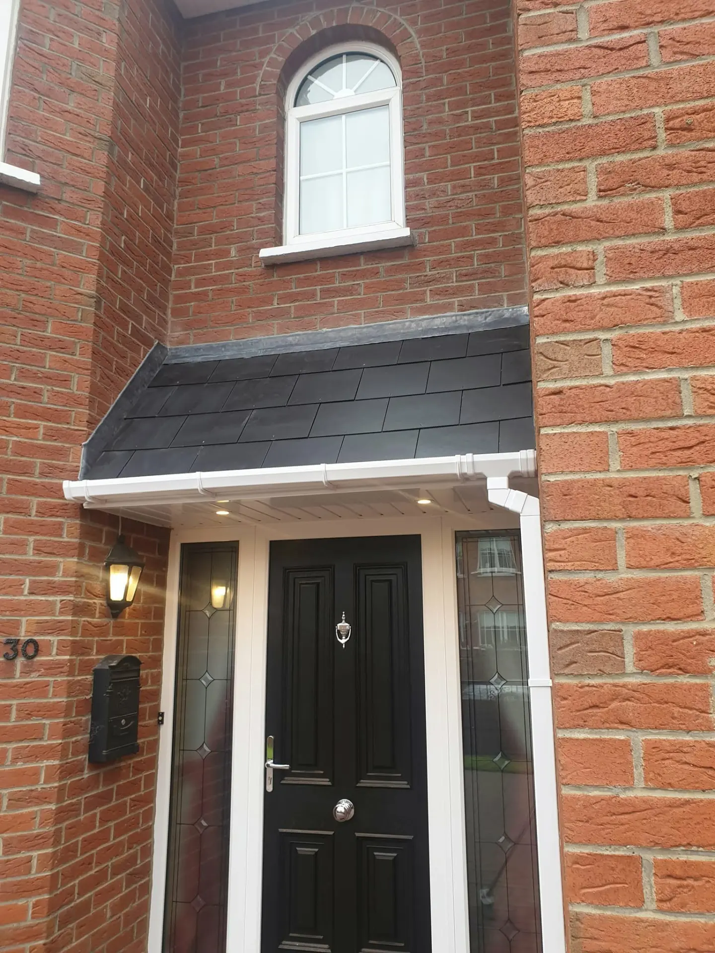 Slate porch canopy roof with lead flashing over a black front door