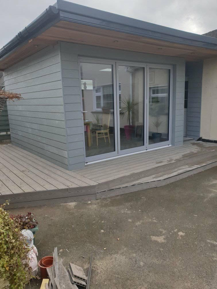 Completed timber-clad garden room extension with bi-fold doors and decking